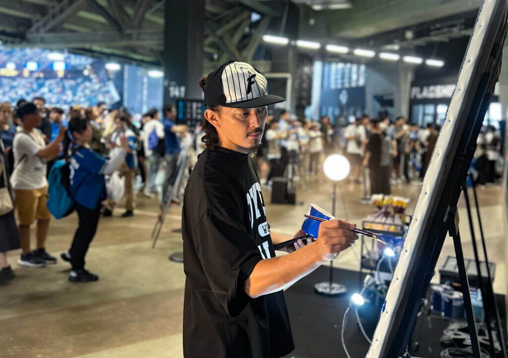 『OVER ALLs展』-試合中に筆を進める画家の山本